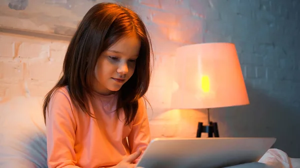 Preteen ragazza utilizzando il computer portatile offuscata sul letto — Foto stock