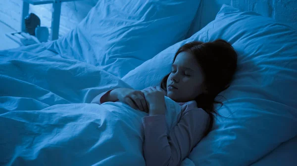 Kid sleeping on bed with white bedding during night — Stock Photo