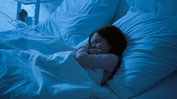 Ragazzo preadolescente che abbraccia la coperta mentre dorme sul letto — Foto stock