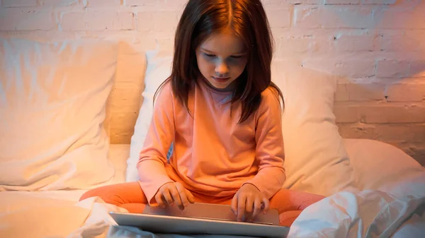 Preteen criança usando laptop enquanto sentado na cama — Fotografia de Stock