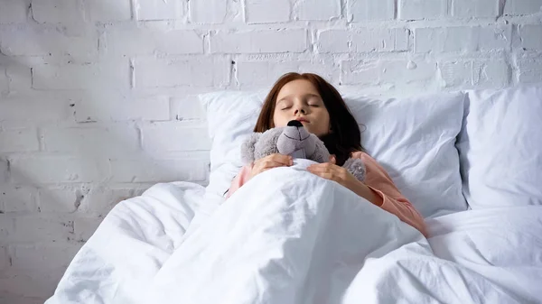 Frühpubertierendes Kind schläft mit Stofftier im Bett — Stockfoto