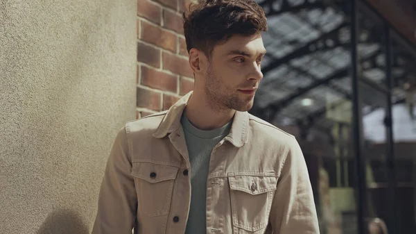 Good-looking man in beige jacket looking away in shopping mall — Photo de stock