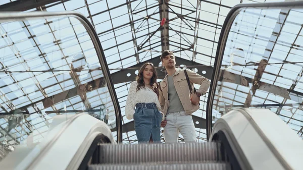 Visão de baixo ângulo do casal perto de escada rolante no centro comercial — Fotografia de Stock