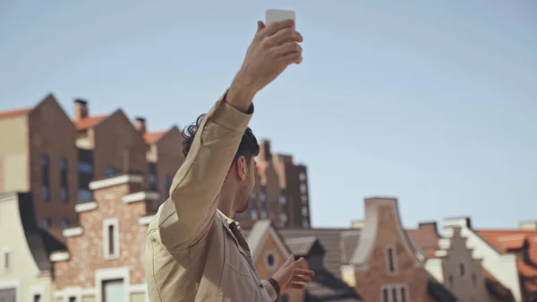 Uomo che tiene smartphone mentre scatta foto di edifici — Foto stock