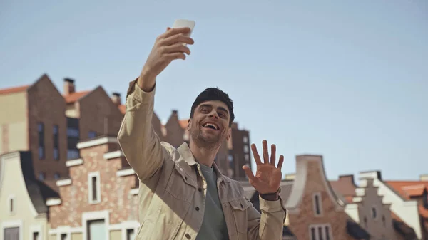 Uomo felice mano agitando mentre ha videochiamata su smartphone — Foto stock