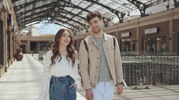 Щасливий чоловік і жінка розмовляють, ходячи разом у торговому центрі — стокове фото
