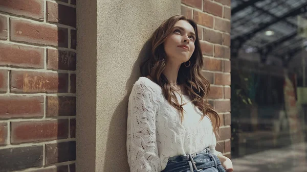 Dreamy young woman looking up near building of shopping mall — Photo de stock