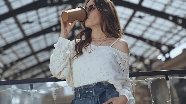 Young stylish woman drinking coffee to go in shopping mall — Photo de stock