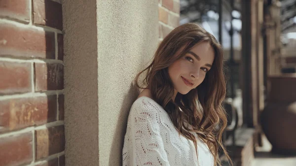 Sonriente mujer joven mirando a la cámara cerca del edificio exterior - foto de stock