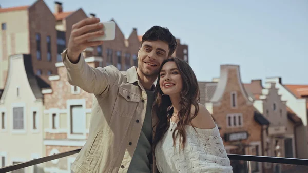 Uomo allegro prendendo selfie con donna felice al di fuori — Foto stock