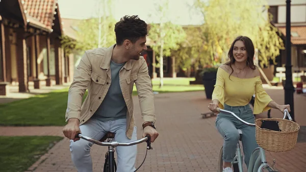 Uomo e donna sorridenti in bicicletta per strada — Foto stock