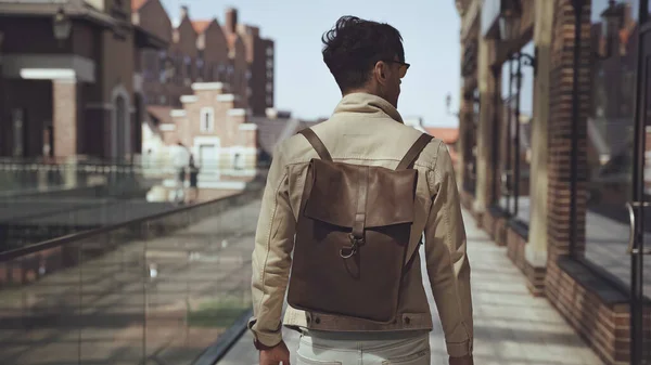 Vista trasera del hombre con estilo con mochila de cuero caminando fuera - foto de stock