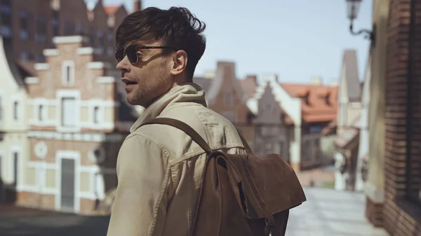 Stilvoller Tourist mit Sonnenbrille und Rucksack steht draußen — Stockfoto