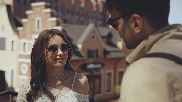 Happy woman in sunglasses looking at blurred man — Photo de stock