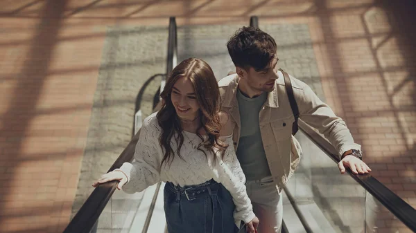 High angle view of happy man and woman on escalator in shopping mall — Photo de stock