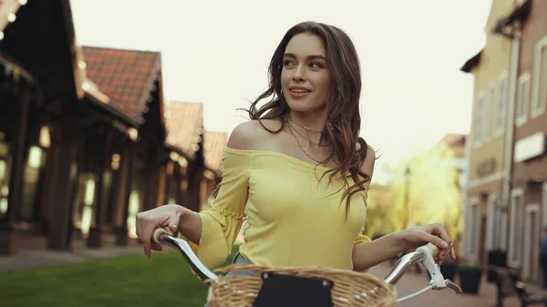 Happy young woman with wavy hair riding bike outside — Stock Photo