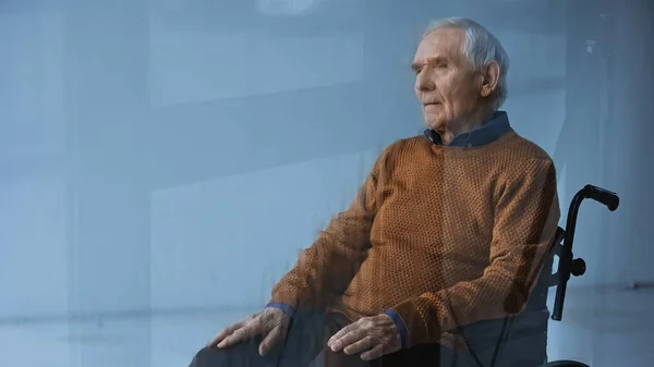 Thoughtful senior man in wheelchair looking away on grey background — Stock Photo