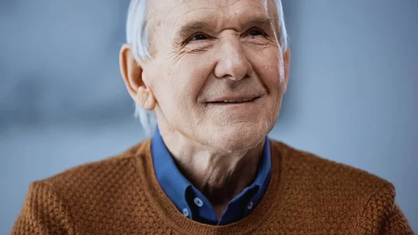 Портрет положительного пожилого человека, смотрящего в сторону на сером фоне — стоковое фото