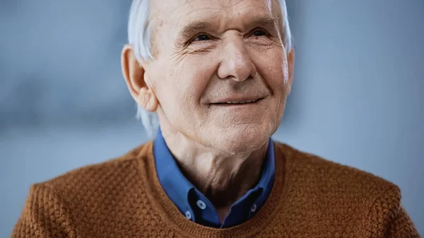 Retrato del anciano positivo mirando hacia otro lado sobre fondo gris - foto de stock