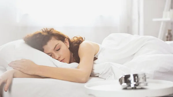 Mujer joven durmiendo cerca de reloj despertador retro - foto de stock