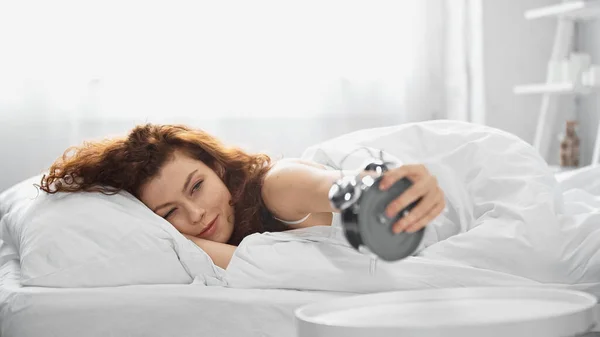 Усміхнена молода жінка тримає ретро будильник — стокове фото