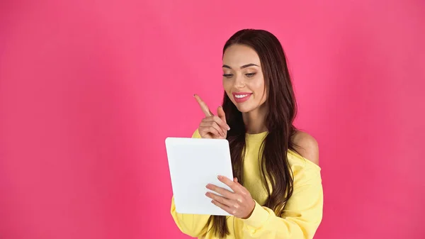 Smiling young adult woman looking at tablet with idea gesture isolated on pink — Photo de stock