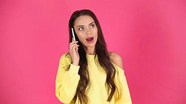 Amazed young adult woman with open mouth speaking on cellphone isolated on pink — Stock Photo