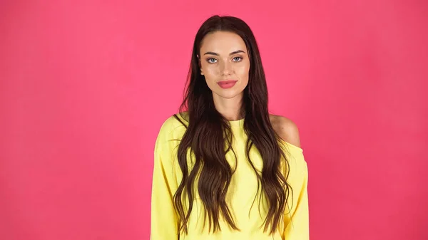 Young adult woman in yellow blouse looking at camera isolated on pink - foto de stock