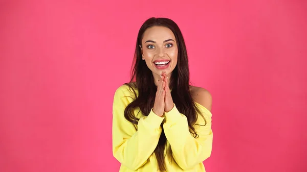 Positive junge erwachsene Frau in gelber Bluse blickt in die Kamera mit betenden Händen isoliert auf rosa — Stockfoto