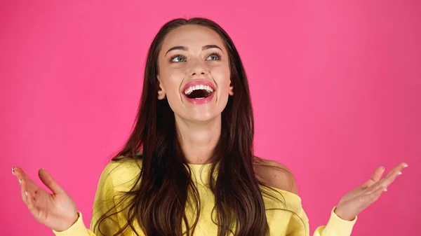 Amazed young adult woman with outstretched hands isolated on pink — Photo de stock