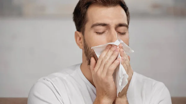 Man with allergy sneezing in tissue at home — Stock Photo