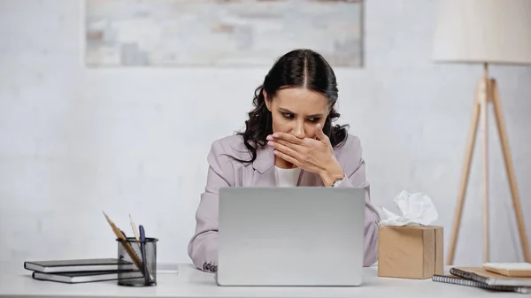 Allergic businesswoman with running nose near laptop on desk — Foto stock