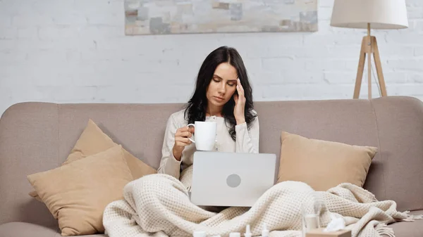 Kranker Freiberufler hält Tasse Tee während er unter Kopfschmerzen leidet — Stockfoto