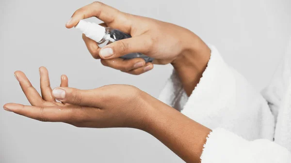 Vue recadrée de la femme afro-américaine en peignoir à l'aide d'un désinfectant pour les mains isolé sur gris — Photo de stock