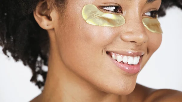 Vue rapprochée de la femme afro-américaine souriante avec des taches d'hydrogel isolées sur gris — Photo de stock