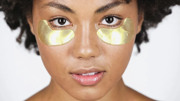 Close up view of african american woman with golden eye patches isolated on grey — Stock Photo