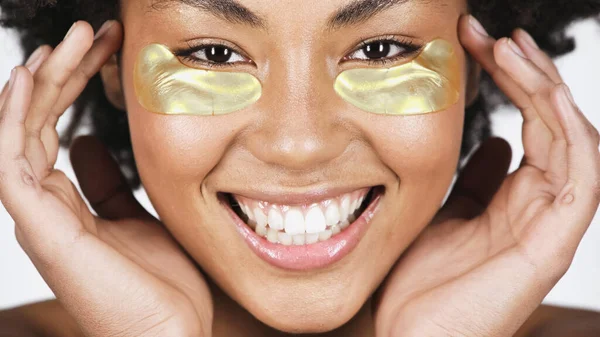 Close up view of positive african american woman in hydrogel eye patches isolated on grey — Stock Photo