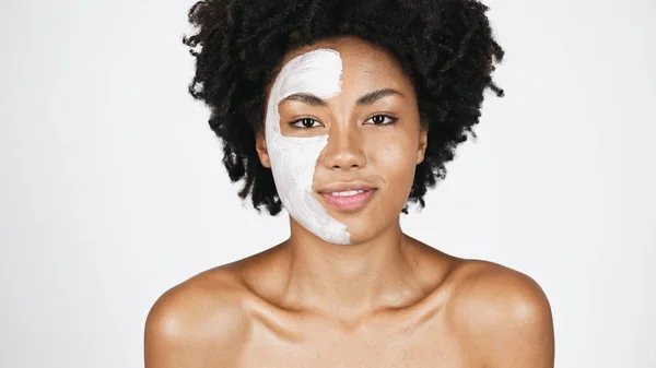 Femme afro-américaine souriante avec masque en argile sur le visage isolé sur gris — Photo de stock