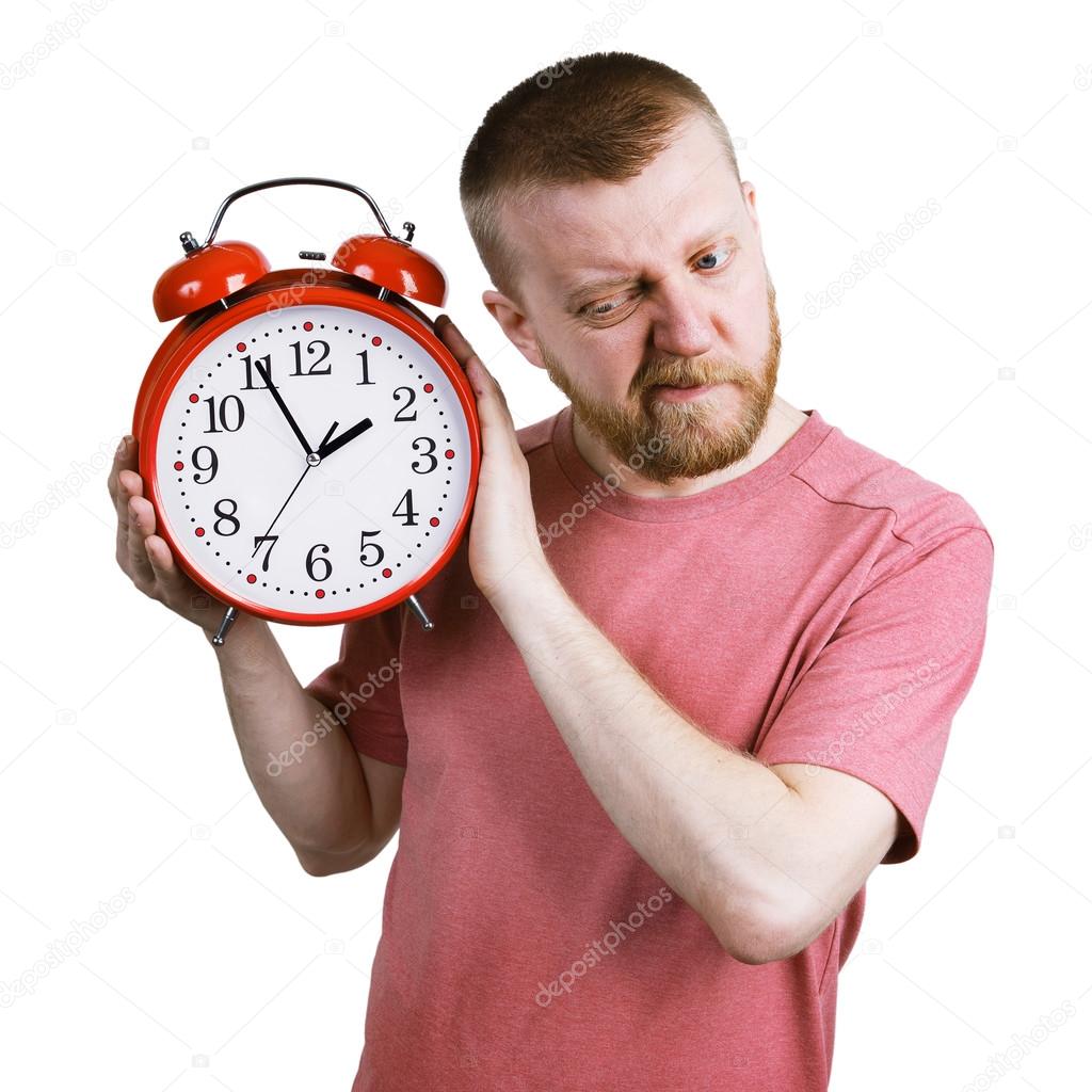 Man listening to the ticking of alarm clock