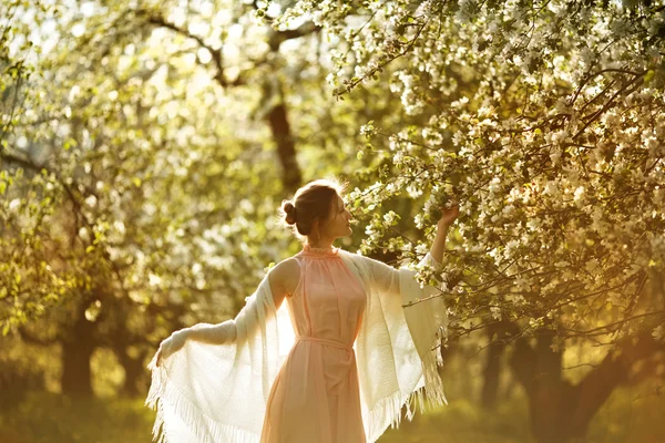 Mulher em um vestido perto de árvore de maçã florescendo — Fotografia de Stock