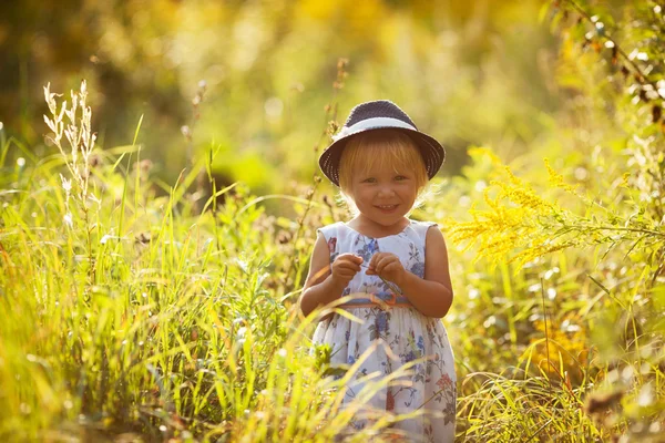 Liten blond flicka i en klänning och hatt — Stockfoto