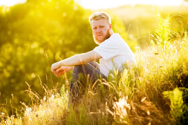 Blonder Mann Sitzt Auf Dem Gras Und Schaut Zur Seite — Stockfoto