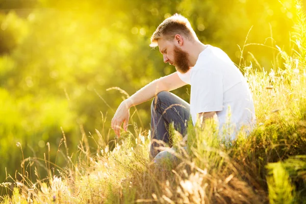 금발에 티셔츠를 젊은이가 여름날 풀밭에 — 스톡 사진