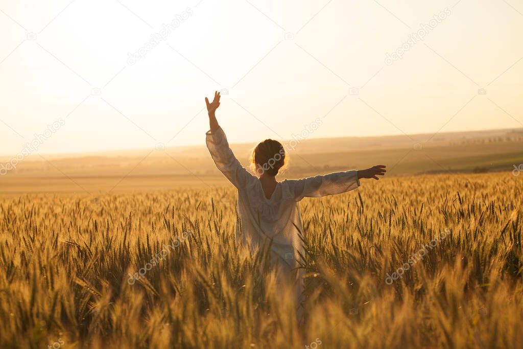 Happy girl in a dress in the middle of a field of ripe rye