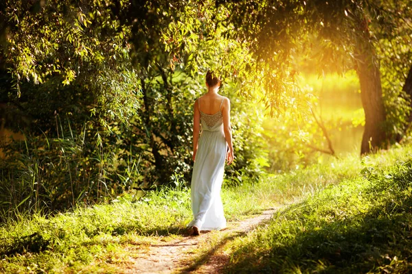 夏の庭を歩く青いドレスの女性 — ストック写真