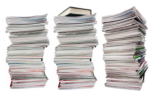 Высокая стопка старых журналов и книга на белом фоне