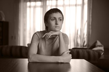 Genç ve güzel bir kadın masada oturuyor ve hayal kuruyor.