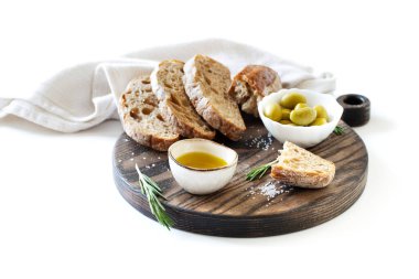 Kesme tahtasında dilimlenmiş ekmek, zeytin ve zeytin yağı.