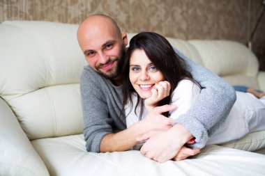 Evdeki kanepede yatan genç çift.