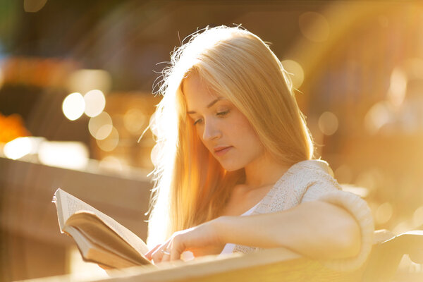 Happy blonde girl reading a book